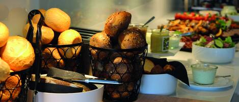 A buffet table with various food items including bread, salads, and a beverage.