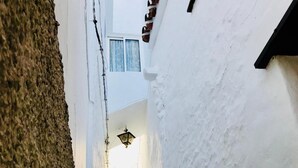 A narrow alleyway with a staircase leading to a higher level, flanked by white walls and a textured stone wall. - HR Mirador (Canillas de Albaida)