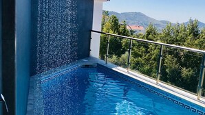 A swimming pool with a water feature, surrounded by a glass balustrade and a view of the landscape. - HR Mirador (Canillas de Albaida)