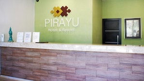 Mostrador de recepción en el Hotel & Resort PIRAYU, con pared verde, un logotipo y mostrador con diseño de panel de madera.