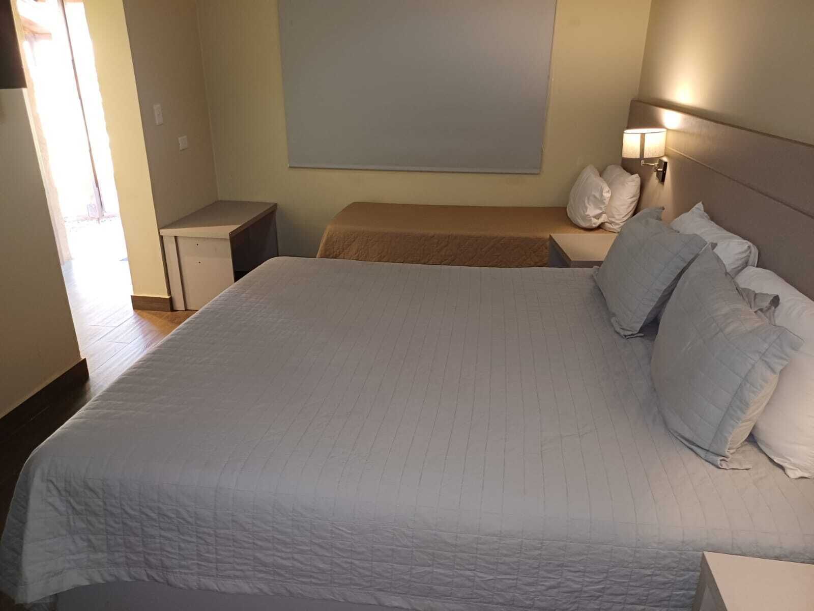 Una habitación de hotel con una cama grande, una mesita de noche y una lámpara de pared.