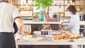 Montaje de bufé con distintos alimentos y una zona de bar al fondo.