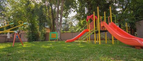 A playground with a red slide and yellow and green climbing structures.