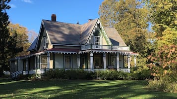 A large, two-story house with a wrap-around porch and a steeply pitched roof.