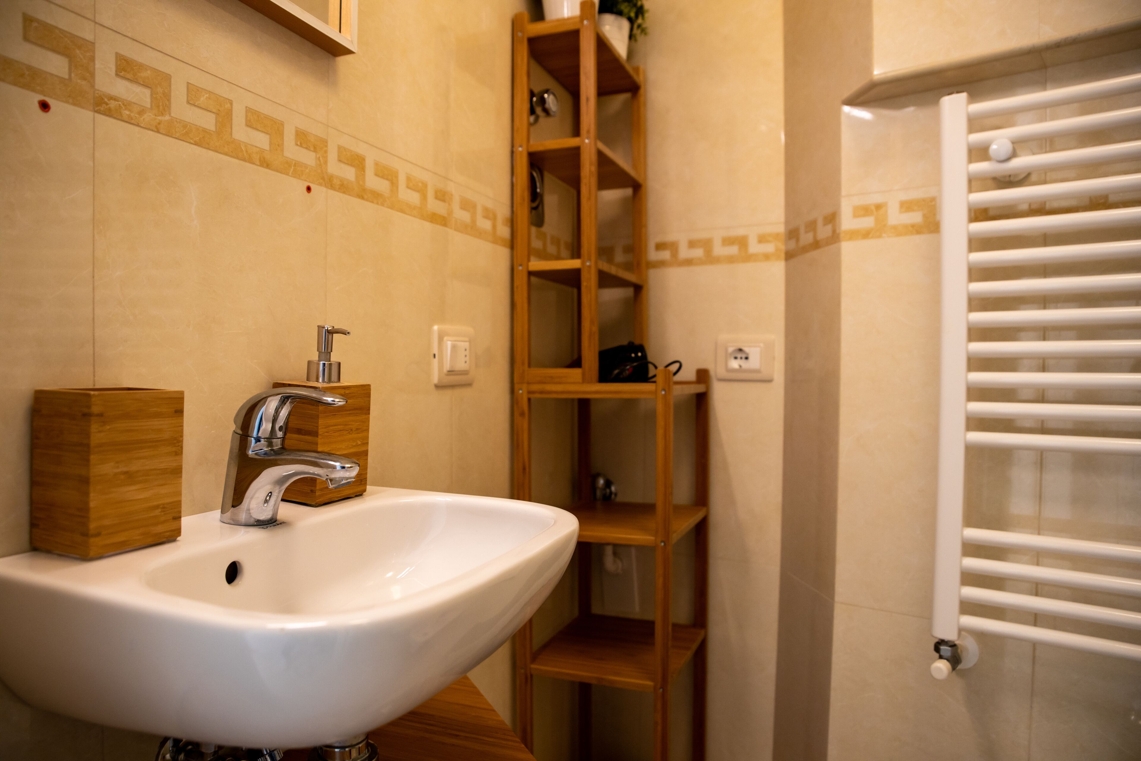 A bathroom with a white sink, wooden shelves, and a towel rack.