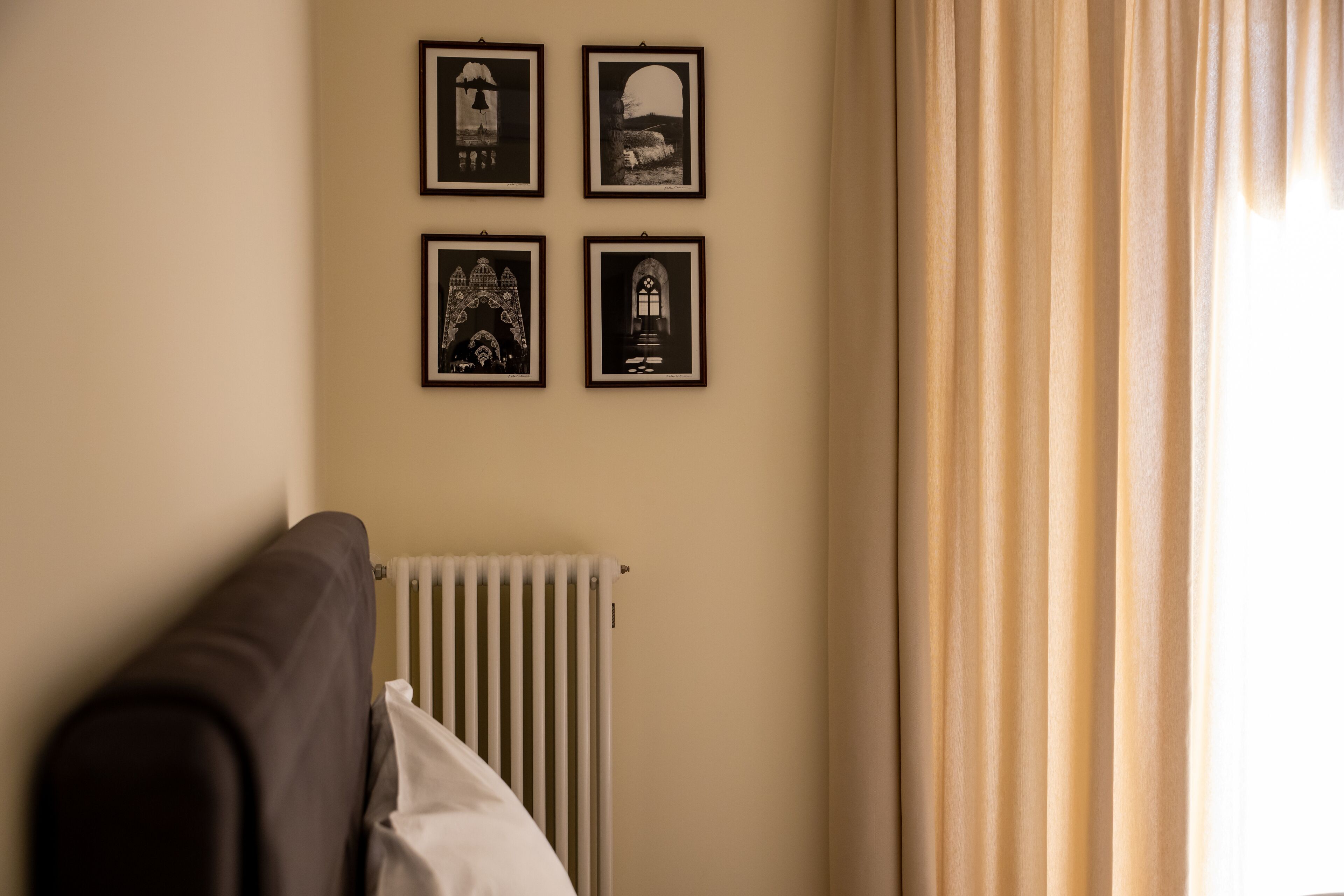 Una habitación con un radiador, un sofá y cuatro cuadros en la pared.