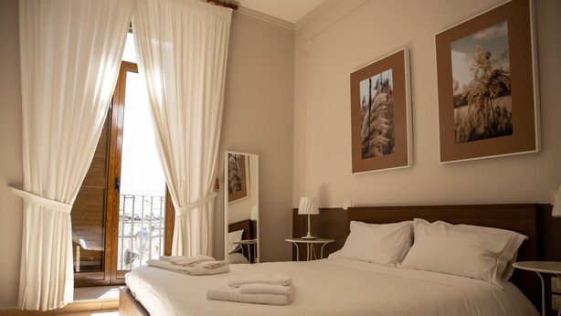 Una habitación de hotel con una cama grande, una mesita, una silla y vistas al exterior.