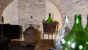 Una habitación acogedora con pared de piedra, cestas de mimbre y una botella verde.