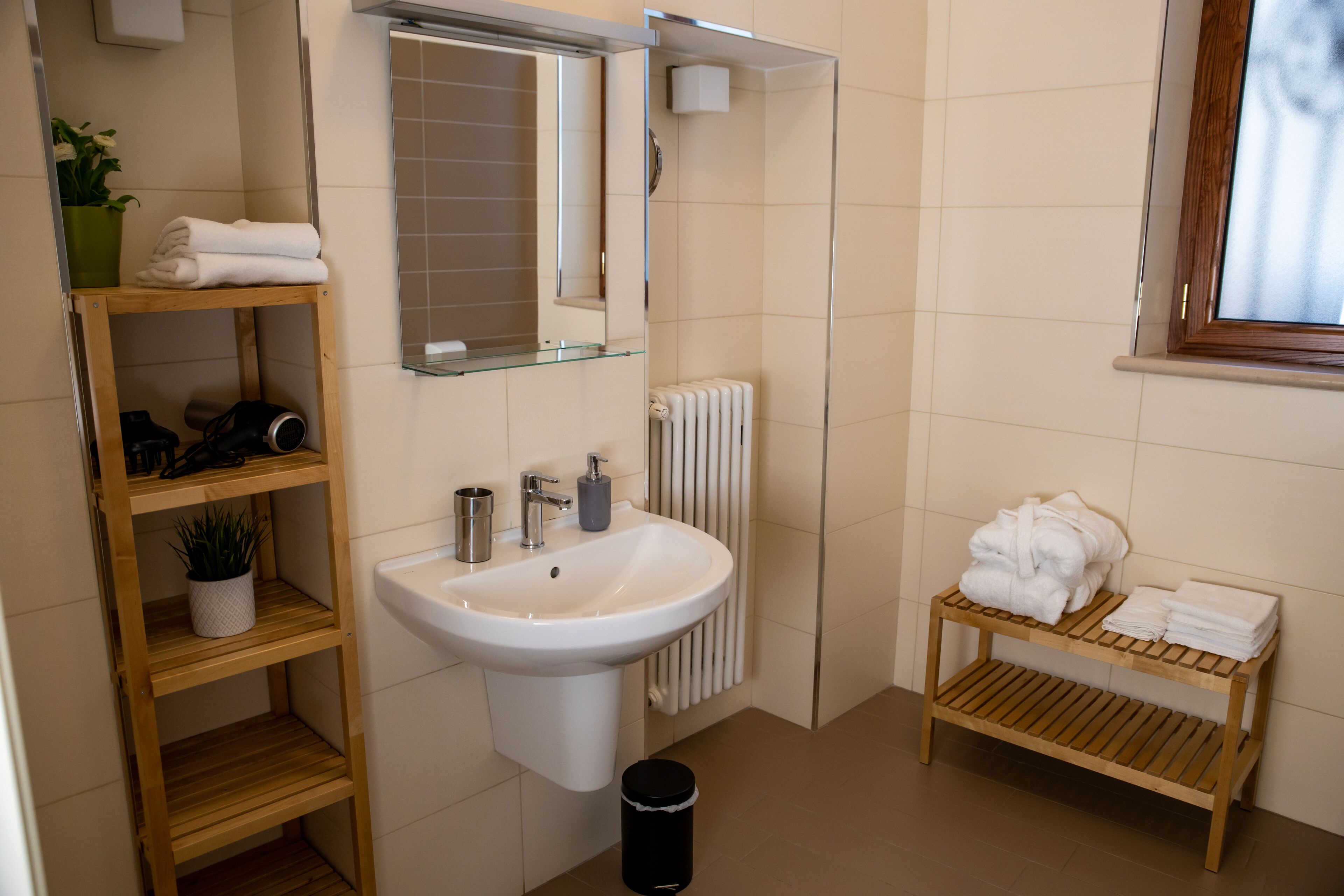 Een badkamer met een wastafel, spiegel, handdoekhouder en een klein plankje met toiletartikelen.