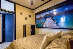 Une chambre d’hôtel avec un grand lit, un téléviseur fixé au mur et une porte.
