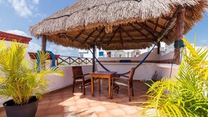 Un patio con techo de paja, muebles de madera y plantas en macetas.