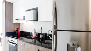 Una cocina moderna con electrodomésticos de acero inoxidable, una encimera negra y armarios de madera.