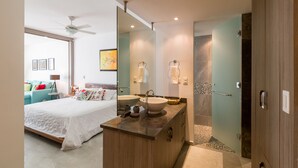 Un dormitorio moderno con una cama grande, una mesita de noche, un ventilador de techo y un ventanal amplio.