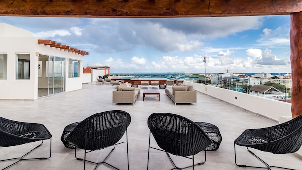 Terraza en la azotea con mobiliario exterior, piscina y vistas a la ciudad.