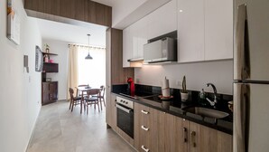 Una cocina moderna con microondas integrado, refrigerador de acero inoxidable y encimera negra.