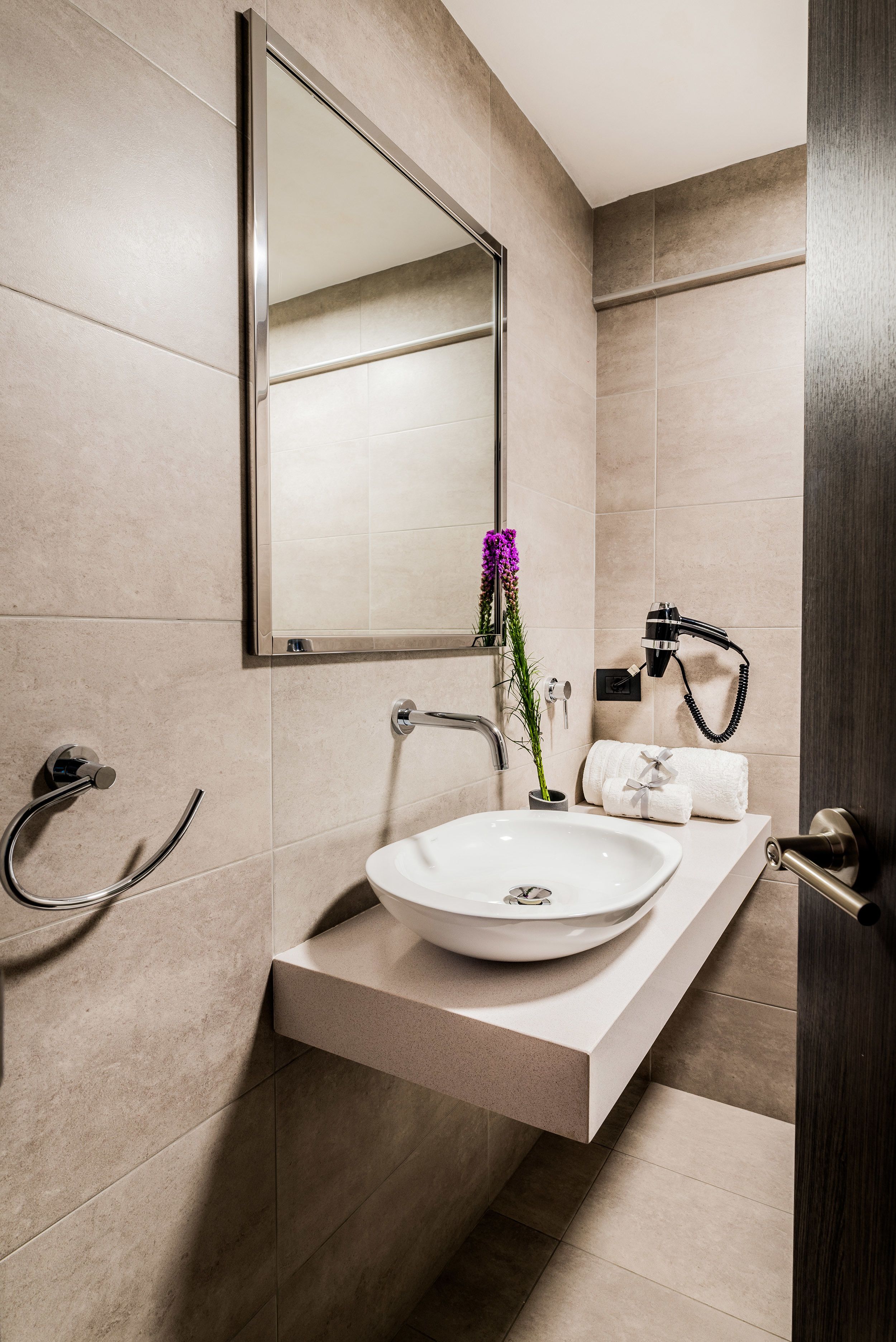 A modern bathroom with a white sink, a mirror, and a towel rack.