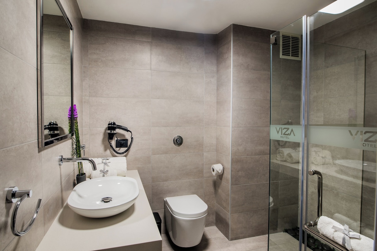 A modern bathroom with a white sink, toilet, and glass shower enclosure.