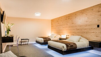 Un dormitorio moderno con dos camas, una pared de acento de madera, un escritorio pequeño y una silla.