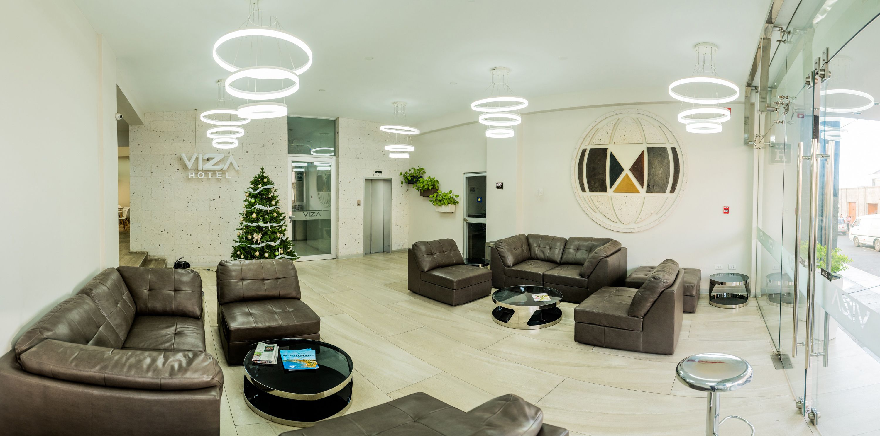 A modern hotel lobby with leather sofas, a glass coffee table, and a Christmas tree.