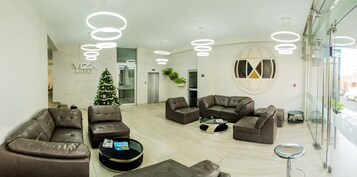 A modern hotel lobby with leather sofas, a glass coffee table, and a Christmas tree.