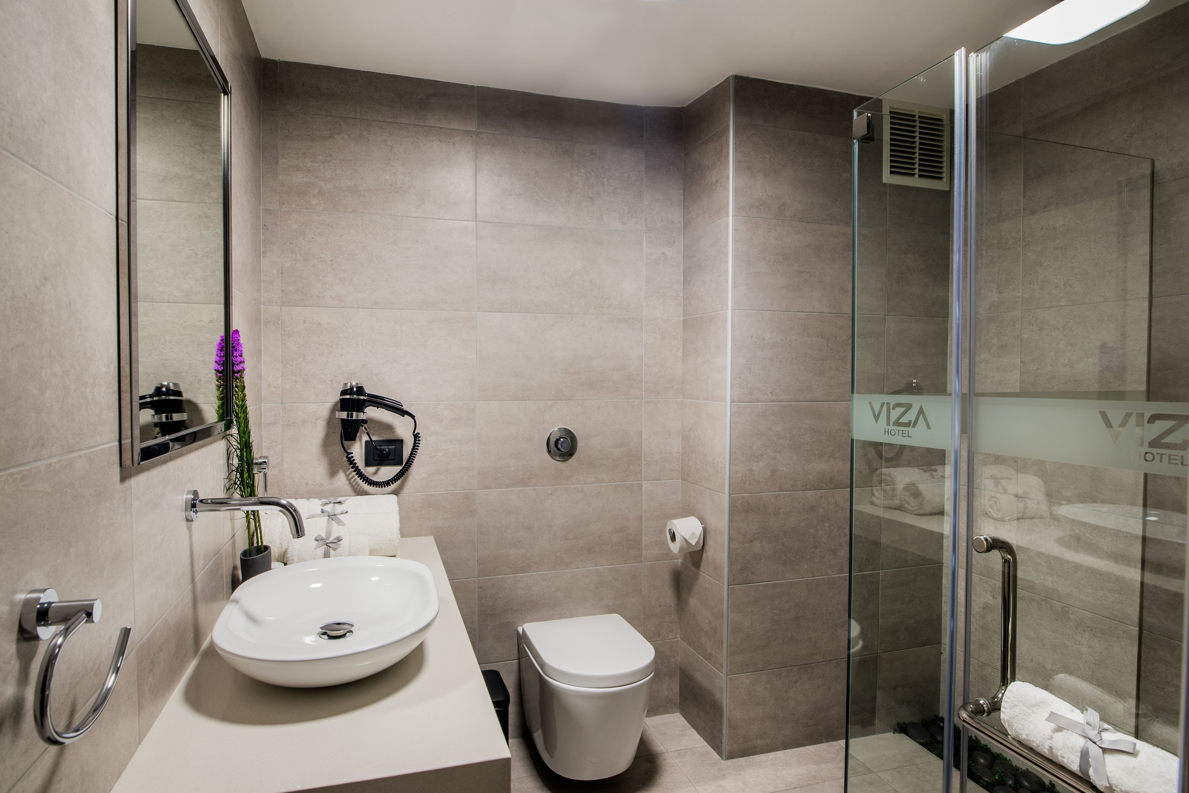 A modern bathroom with a white sink, toilet, and glass shower enclosure.