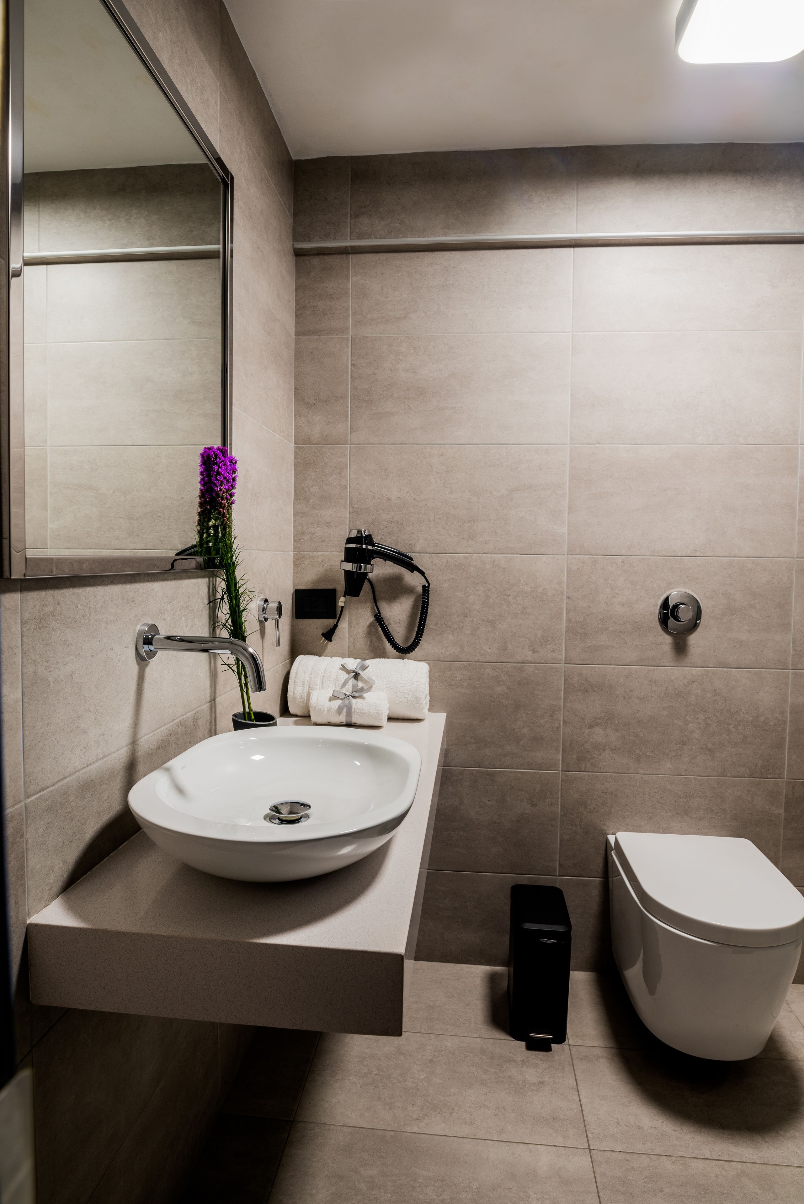 Un baño moderno con un lavamanos blanco, un inodoro y una ducha.