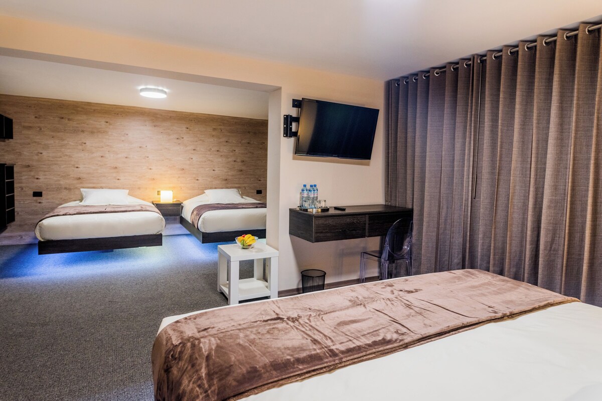 Ein Hotelzimmer mit zwei Betten, einem Schreibtisch, einem Fernseher und einem Vorhang.