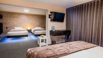 Una habitación de hotel con dos camas, un escritorio, un televisor y una cortina.