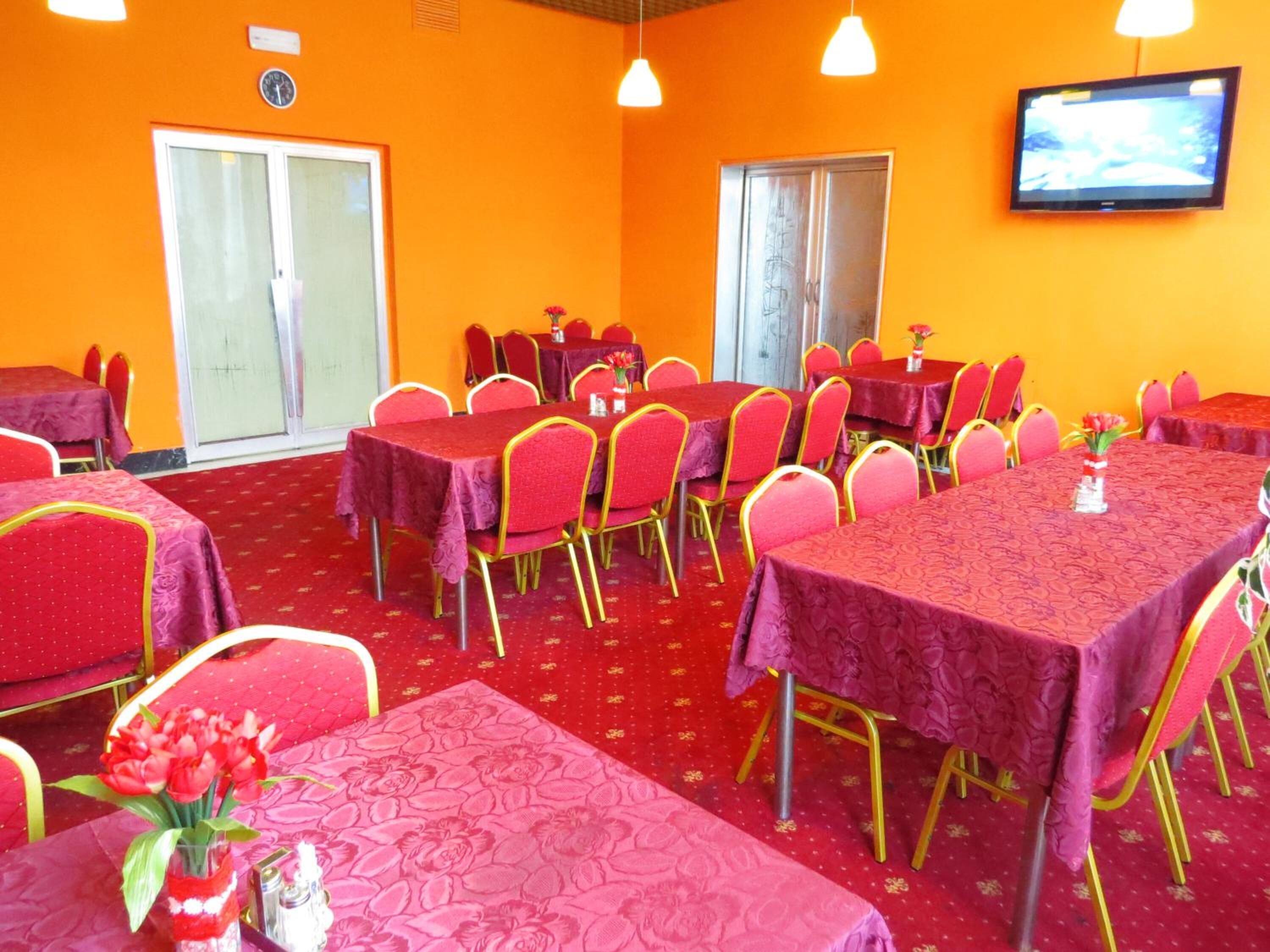 A conference room with tables and chairs, a television on the wall, and a clock on the wall.