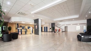 Un vestíbulo amplio con mostrador de recepción, zonas de estar y una escalera.
