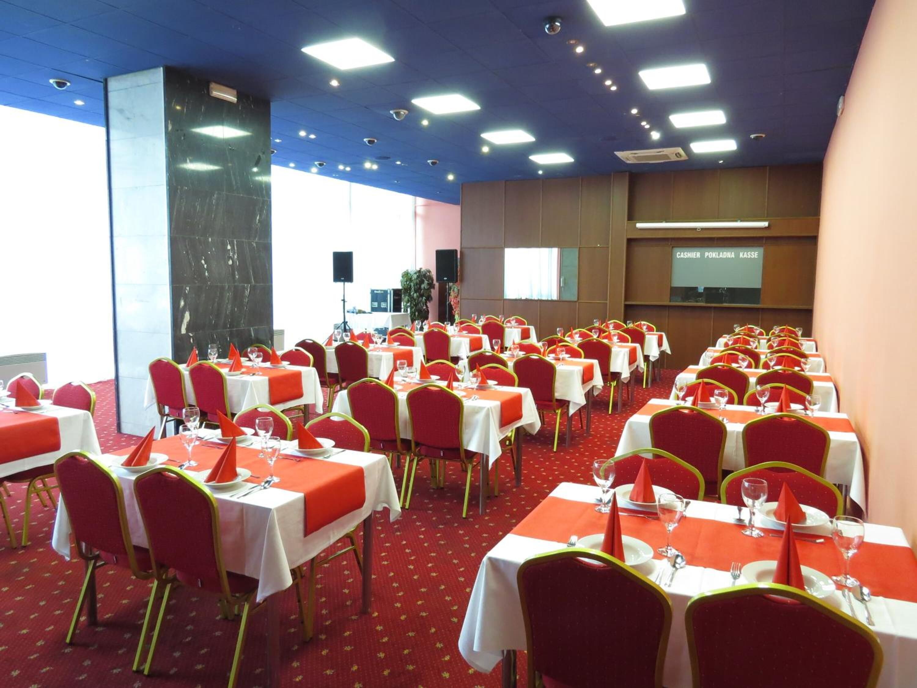 Un salón de conferencias con varias mesas y sillas, dispuesto para una reunión o evento.