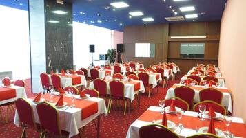 Un salón de conferencias con varias mesas y sillas, dispuesto para una reunión o evento.