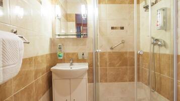 Une salle de bain avec une douche à parois de verre, un lavabo avec un miroir au-dessus et des toilettes.