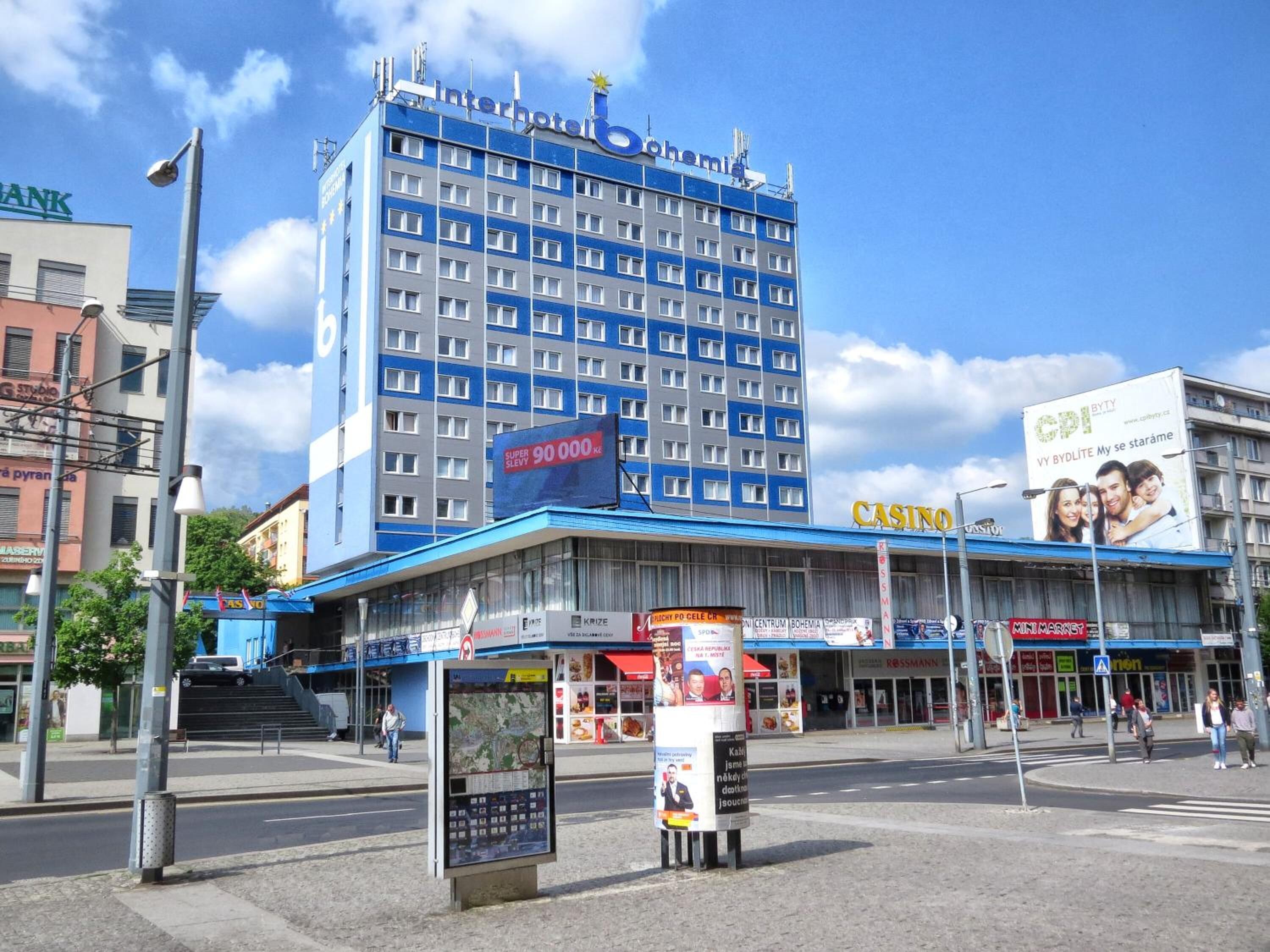 Ein mehrstöckiges Hotel mit einer markanten blauen Fassade, einem Casinoschild und einer großen Werbetafel, die eine Sonderaktion bewirbt.
