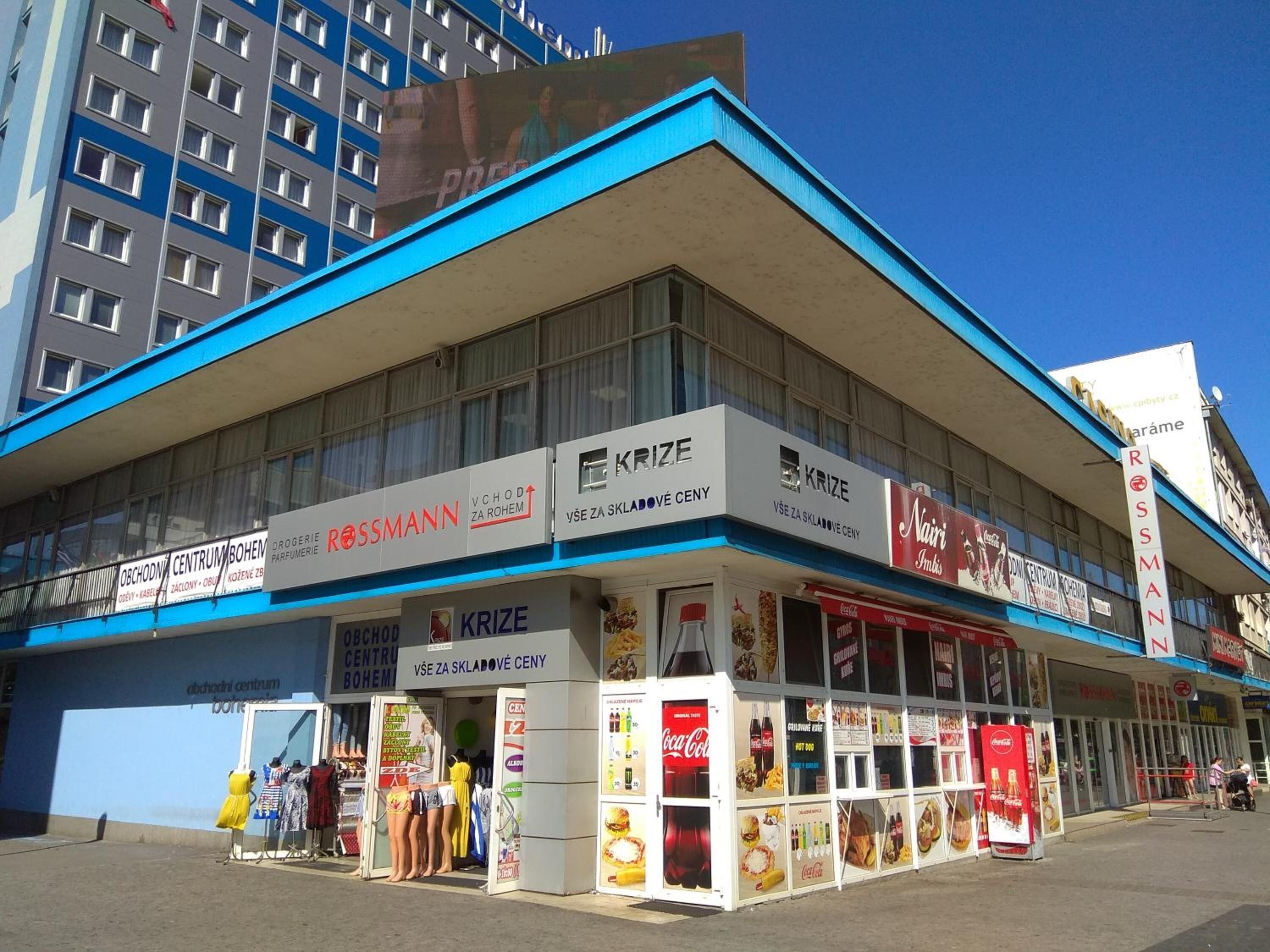 A building with multiple storefronts, including a Rossmann pharmacy and a Krize store.