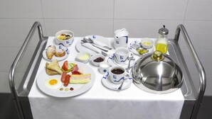 Un desayuno servido en una bandeja con huevos, salchichas, queso, tostadas y diversos condimentos.