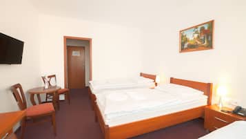 Habitación de hotel con cama de madera, un escritorio con silla, televisión y un cuadro en la pared.