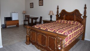 Une chambre à coucher avec un lit à baldaquin en bois, un petit bureau avec une lampe et un réfrigérateur.