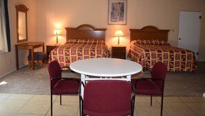 Une chambre avec deux lits, une table ronde et quatre chaises.