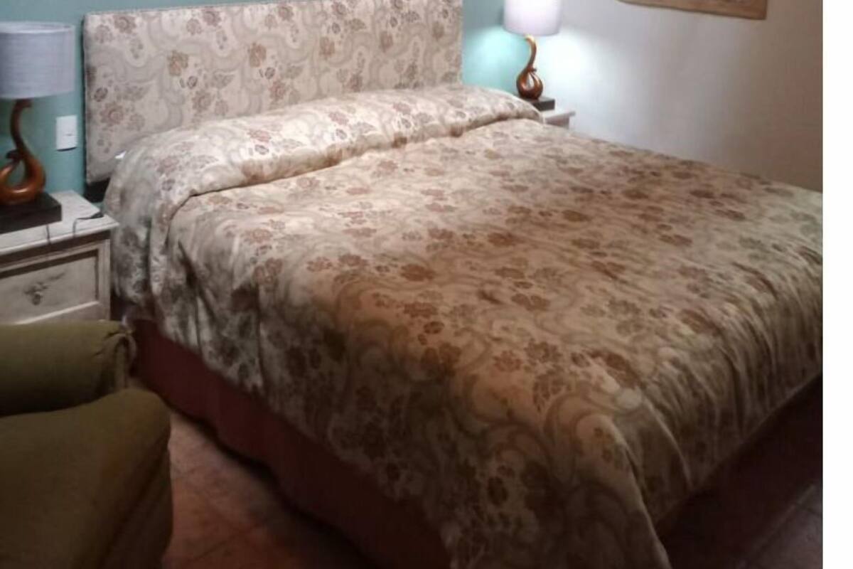 Ein Schlafzimmer mit einem Bett, einem Nachttisch, einer Lampe, einem Bild und einer Wanddekoration.