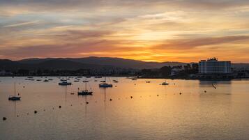 A coastal view with boats and buildings during sunset.