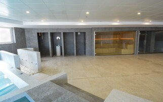 A modern bathroom with a large bathtub, a shower area, and a glass-enclosed seating area.