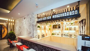 Un espace bar avec un comptoir, des sièges et un mur décoré d’illustrations.