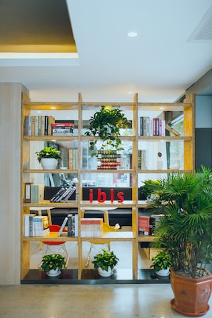 Una estanteria amb llibres i plantes, una cadira vermella, i la paraula 'ibis' a l'estanteria.