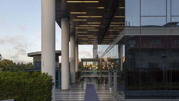 Een moderne hotelentree met een duidelijke doorgang naar de ingang, grote pilaren en een bord met de tekst 
