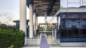 Un bâtiment moderne doté d’une galerie couverte, de grandes colonnes et d’une entrée en verre.