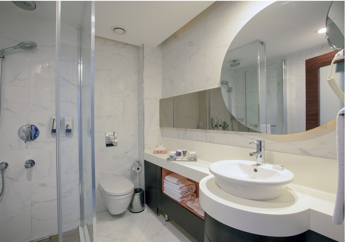 A modern bathroom with a glass-enclosed shower, a white sink, and a large mirror.
