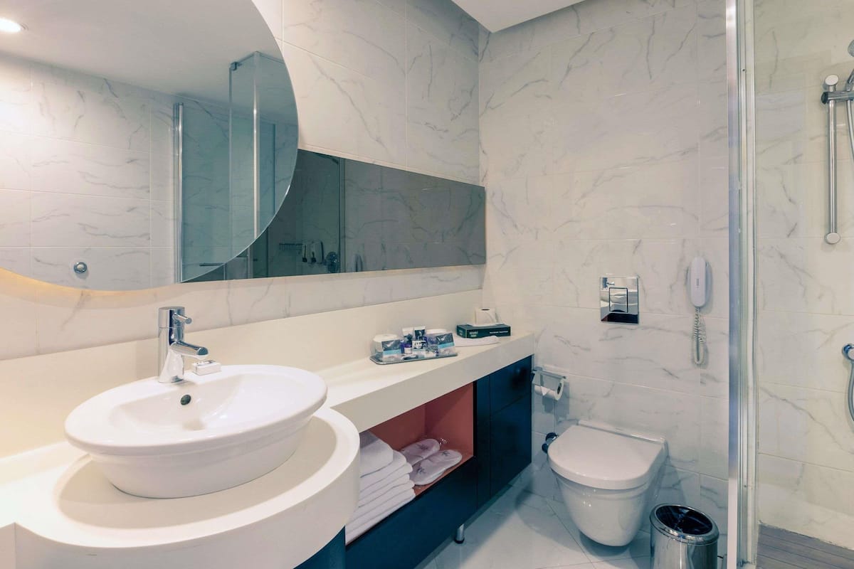 Ein modernes Badezimmer mit großem Spiegel, Waschbecken, Toilette und Duschbereich.