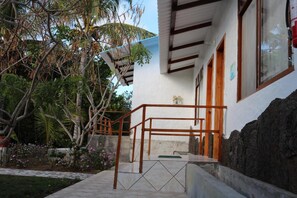 A building with a concrete staircase leading to a wooden door, surrounded by tropical vegetation. - Cartago Bay (Puerto Villamil)