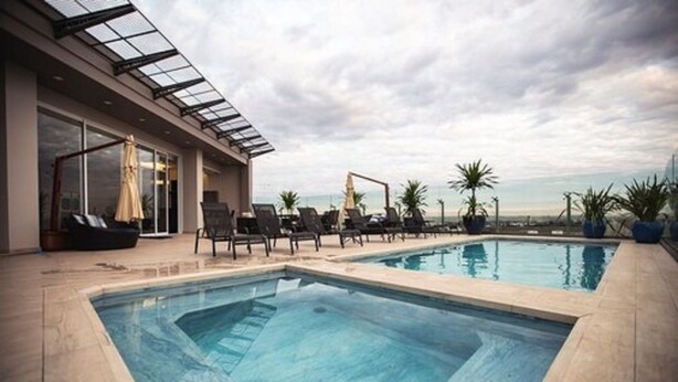 A rooftop pool with lounge chairs and a glass-enclosed patio. - Hotel Transamerica Maringá (Maringá)